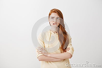 Trying to handle emotions and not to worry. Anxious redhead woman in trendy hoodie, standing with crossed hands to Stock Photo