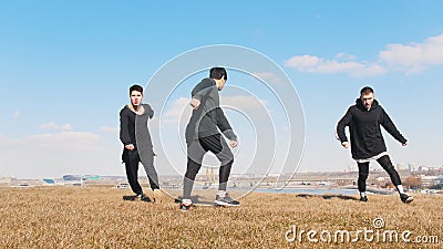 Três homens novos que executam synchronously a aleta acrobática na grama video estoque Três homens novos que executam synchronously a aleta acrobática na grama video estoque