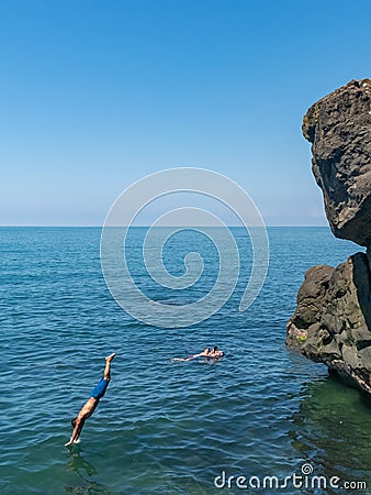 Tsikhisdziri, Georgia - 07 August, 2020: Man jumping from high rock to the see Editorial Stock Photo
