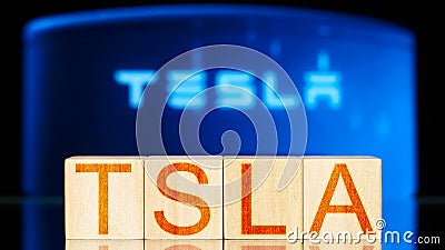 tsla. wooden blocks with tsla lettering on blue background with electric charger. Editorial Stock Photo