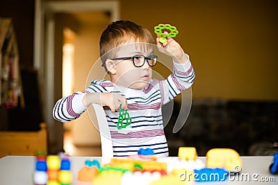 Little boy with syndrome dawn in the black glasses playing with blocks Stock Photo