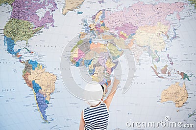 Little kid in captain cap pointing at world map with finger direction tour Stock Photo