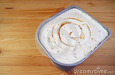 Tub of Delectable Salted Caramel Macadamia Nut Ice Cream on Wooden Table Stock Photo