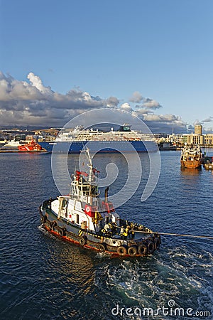 A Tug Boat attached to a Vessel with a Heaving Rope manoeuvring the Vessel into position Editorial Stock Photo