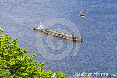 A tug boat hauls a large, empty barge down wide Dnipro river dirung sunny day. Seafaring, navigation on river Stock Photo