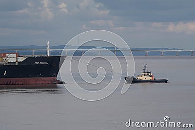 Tugboat works a freighter Editorial Stock Photo