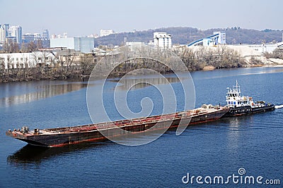 A tugboat with a barge is sailing along the Dnieper Editorial Stock Photo