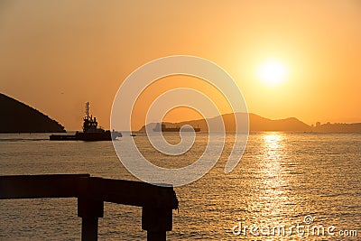 Tugboat going to fetch a ship during sunset Stock Photo