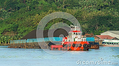 Tugboat pulling barge full of black coal in Mahakam river, Borneo, indonesia Stock Photo