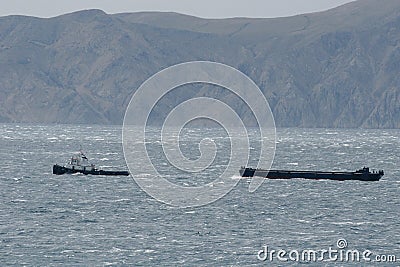 Tugboat pulling ship lost in bora Stock Photo