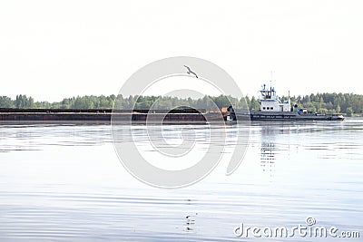 Tugboat pushes sand debris along the river Stock Photo