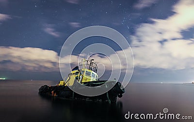 Tugboat ran aground, starry night sky with clouds. Stock Photo