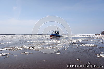 a tugboat sails along a large full-flowing spring river during the ice drift. sunny day, Editorial Stock Photo