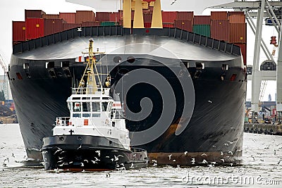 Tugboat towing freighter in harbor Stock Photo