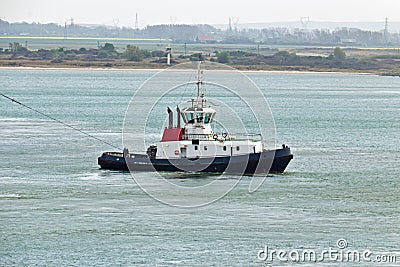Tugboat towing ship in harbor Stock Photo