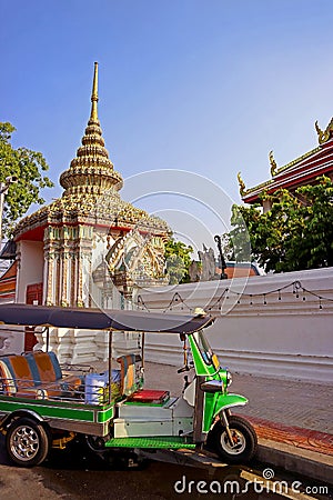 Tuk-tuk taxi in front of the ornate gate of Temple of the Reclining Buddha, Bangkok, Thailand Stock Photo