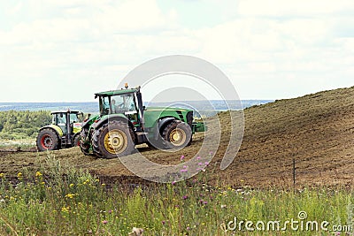 Tula region, Russia, 08.05.2022 Two tractors at the silo compact freshly cut heavy corn with wheels, fermented corn will Editorial Stock Photo