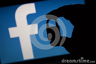 Tula, Russia - August 28, 2018: Facebook security issues. Silhouette of a hand holding a padlock infront . Editorial Stock Photo