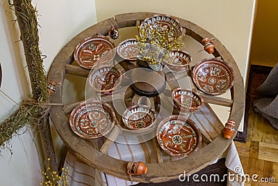 Tulchyn, Ukraine - 06.10.2020: traditional Ukrainian Podillia ornament painting style, clay plate on a wooden wagon wheel Editorial Stock Photo