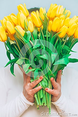 Tulips. Bright bouquet of yellow tulips in female hands. Spring flowers. Flowers tulips for mother, wife, girlfriend etc, conceptu Stock Photo