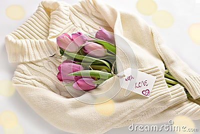 Tulips wrapped in a warm wool sweater with love words on paper label Stock Photo