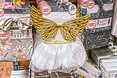 Tiny angel costume for baby with gold quilted wings hanging on retail store rack for sale Editorial Stock Photo