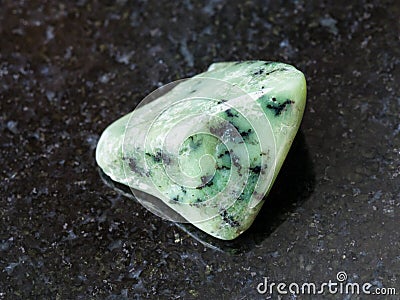 tumbled green Grossular gemstone on dark Stock Photo