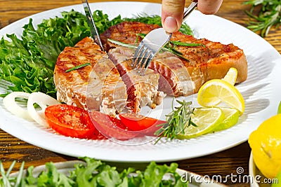 Tuna steak cooked on the electric grill. tunafish served on a plate with fresh herbs and vegetables. healthy nutritious Stock Photo