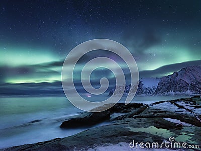 Tungeneset rocks and Aurora Borealis light. Stars trails and northern light. Reflections on the water surface. Senja islands, Norw Stock Photo