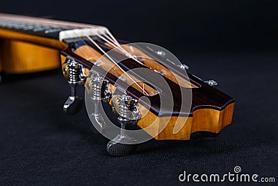 Tuning pegs on wooden machine head of six strings acoustic guitar neck on black background Stock Photo