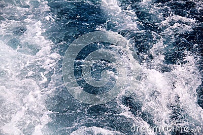 Turbulence made by foam of sea water from a high-speed yacht on surface of sea. Blue sea waves with lot of sea foam. Stock Photo