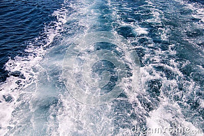 Turbulence made by foam of sea water from a high-speed yacht on surface of sea. Blue sea waves with lot of sea foam. Stock Photo