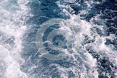 Turbulence made by foam of sea water from a high-speed yacht on surface of sea. Blue sea waves with lot of sea foam. Stock Photo