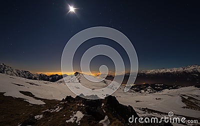 Turin city lights, night view from snow covered Alps by moonlight. Moon and Orion constellation, clear sky, fisheye lens. Italy. Stock Photo