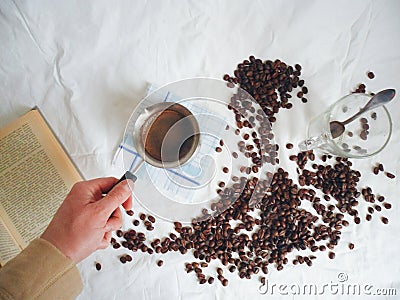 Turka for brewing coffee, a book, a cup with a spoon and coffee beans Stock Photo