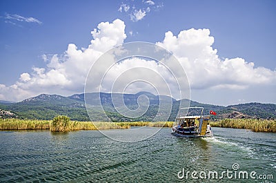 TURKEY, DALYAN, MUGLA - JULY 19, 2016 Pleasure boat with tourists in the mouth of the Dalyan River under Lycian tombs Editorial Stock Photo