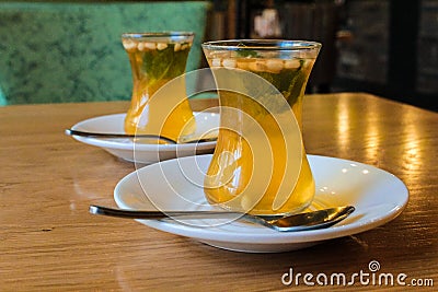 Turkish citrus tea in small cups, with the addition of pine nuts and mint leaves. Stock Photo