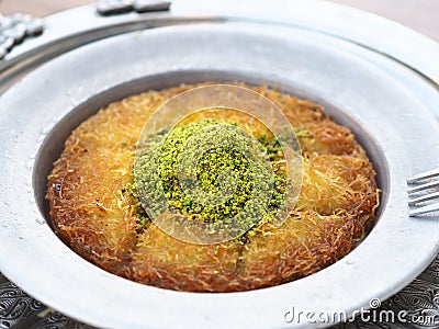 Turkish kunefe dessert in special serving dish with green pistachio Stock Photo