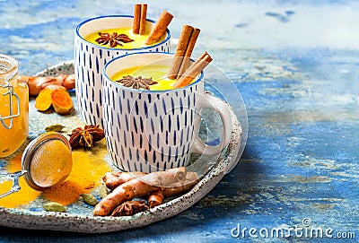 Turmeric golden milk latte with cinnamon sticks and honey. Detox, immune boosting, anti inflammatory healthy cozy drink. Stock Photo