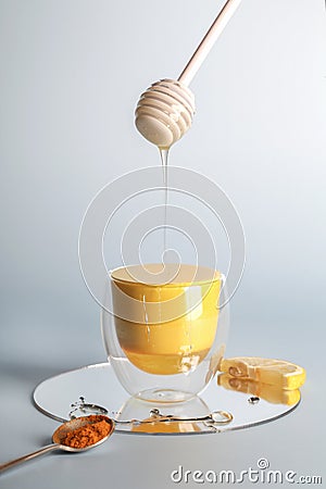 Turmeric, golden milk with powder on spoon , honey flowing from stick and lemon on blue background Stock Photo