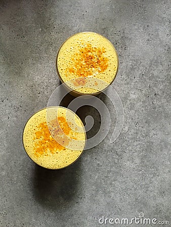 Turmeric lassi (orange smoothie) garnished with turmeric in two glasses Stock Photo