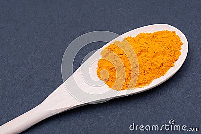 Turmeric powder in handmade wooden spoon on dark. Curcuma longa of the ginger family. Stock Photo