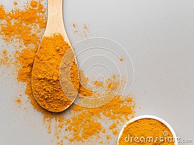 Turmeric powder. Traditional indian golden healthy spice in wooden spoon and white bowl on gray background. Top view Stock Photo