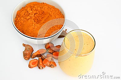 Turmeric smoothie and turmeric powder in bowl with pieces of turmeric root isolated on white Stock Photo