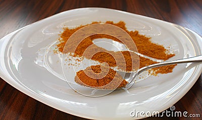 Turmeric spoon closeup. Spoon and portion of turmeric on white plate. Wooden background Stock Photo