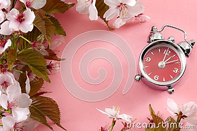 Turn clocks on hour ahead, star of daylight savings time and reminder to spring forward concept with alarm clock on pink Stock Photo