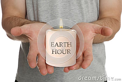 Turn off lights for Earth hour. Man holding burning candle on white background, closeup Stock Photo