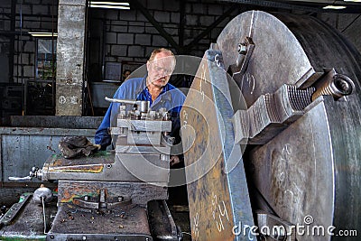 Turner machine operator controls processing of metal big turning Editorial Stock Photo