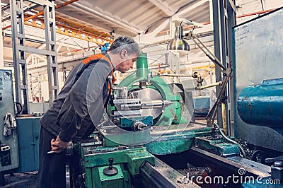 Turner for the machine, the machine operator controls the technological process of cutting and metal processing Stock Photo