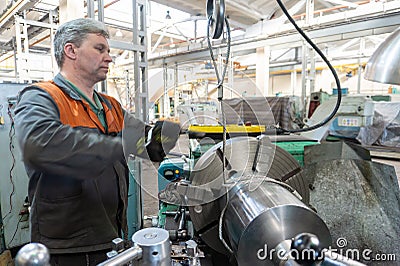 Turner worker manages the metalworking process of mechanical cutting on a lathe Stock Photo